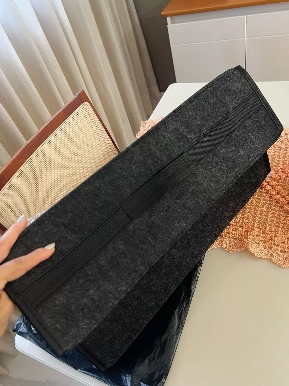 Foto de cliente: organizador fechado sendo sustentado por uma mão pela alça superior